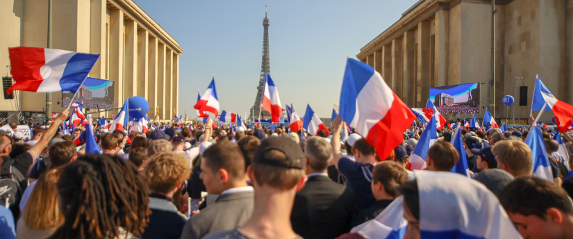 A crowd of people waving French flags in front of the Eiffel Tower during the French elections 2024