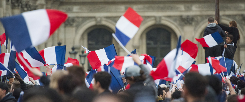 A group of individuals waving French flags in front of a historic building