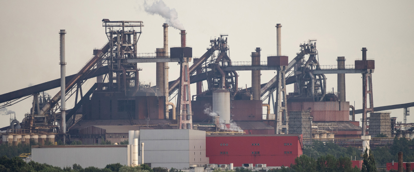Industrial factory with multiple chimneys emitting smoke.