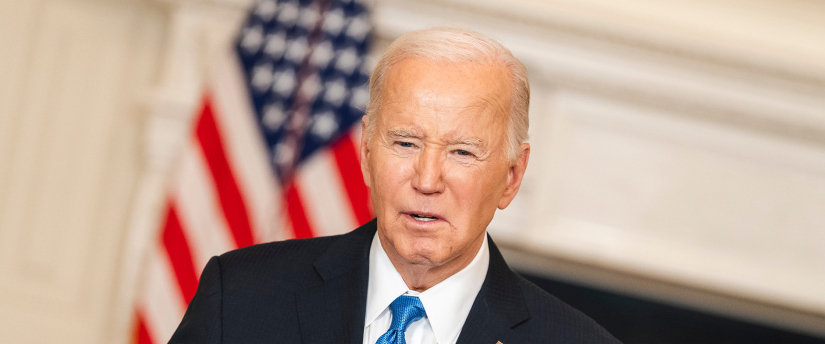 President Biden delivers a speech at a podium with the American flag in the background.