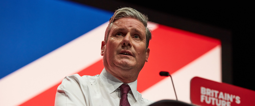 Starmer addressing crowd at UK elections, standing at podium with Big Ben visible.