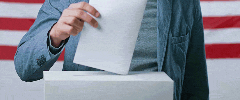 A person participating in the voting process by inserting a paper into a ballot box.