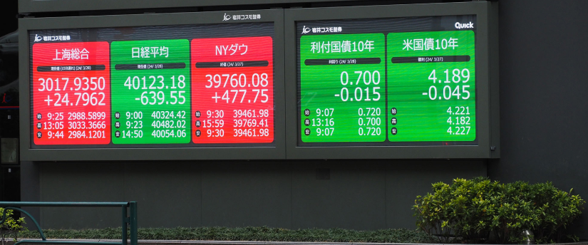 A large electronic display shows fluctuating stock prices in front of a modern financial building.