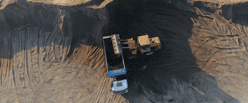 A truck navigates through a sandy landscape, leaving tracks in the soft terrain under a clear sky.