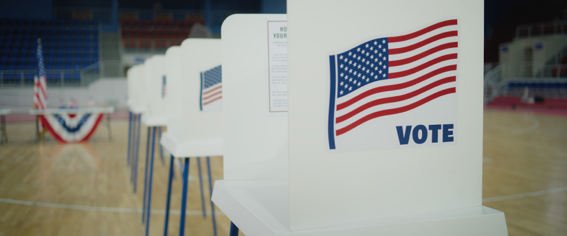 Voting booths in a row with American flag on top.
