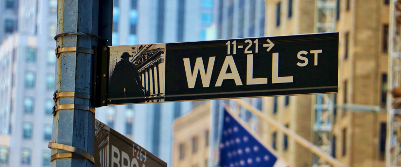 A street sign stands prominently in the foreground, with a building visible in the background.