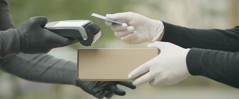 An individual wearing gloves presents a box to another person, illustrating a gesture of giving and cooperation.