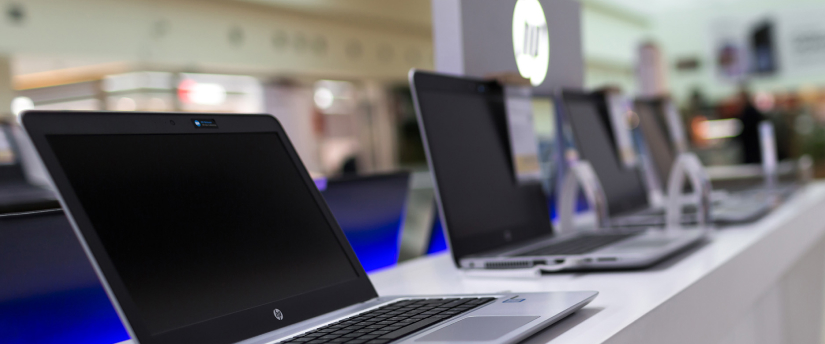 Multiple laptops lined up on a white counter, highlighting a minimalist workspace with a focus on technology.