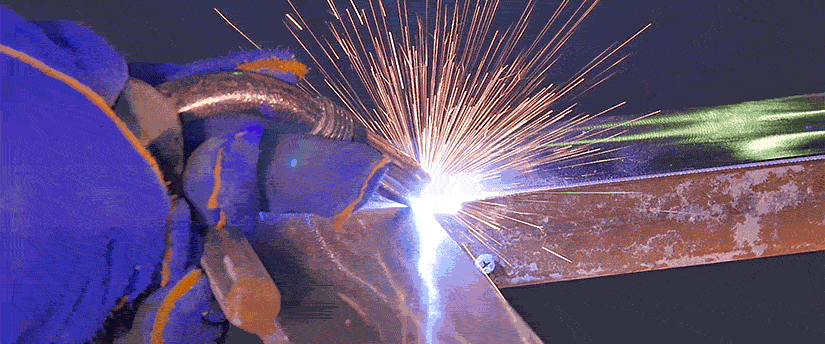 A skilled technician performing welding with a torch, illuminating the workspace with bright sparks and intense heat.