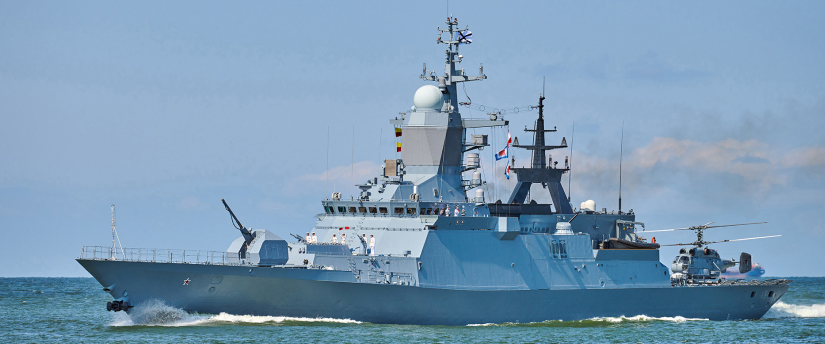 A prominent blue military vessel sails through the ocean, representing advancements in aerospace security and investment opportunities