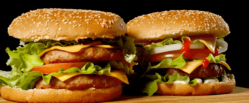 Two delicious Mac hamburgers placed on a wooden cutting board, ready to be enjoyed as a satisfying meal.