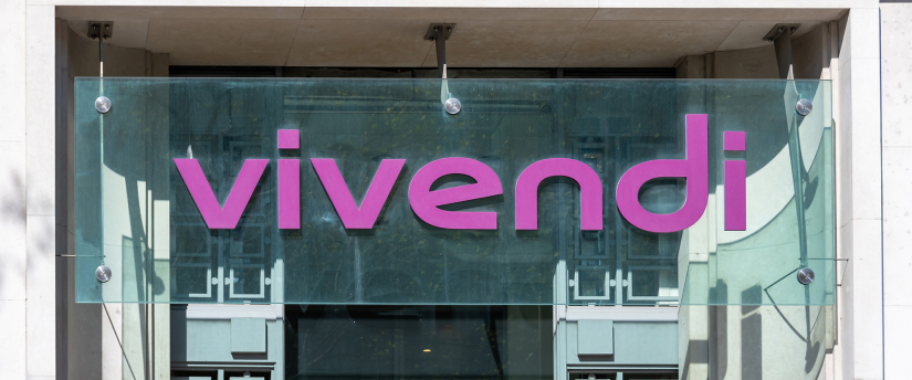 A pink sign on a building displaying the word "Vivendi" in bold letters against a clear sky backdrop.