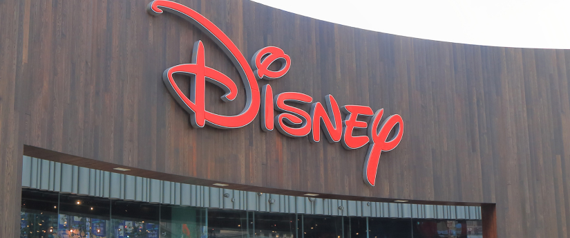 Image of the Walt Disney logo displayed on a building, featuring bold, stylized lettering against a modern architectural backdrop 