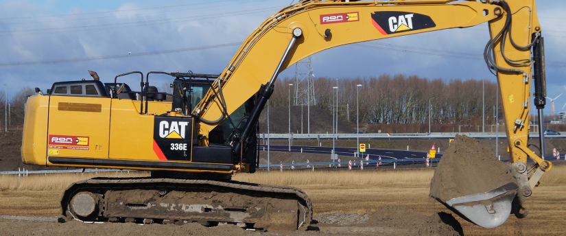 A yellow and black excavator is seen digging into the earth, demonstrating its robust capabilities in excavation work.