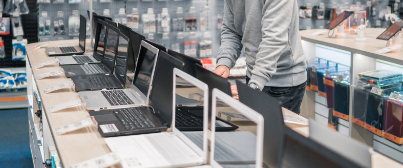 A man poses in front of multiple laptops, highlighting a tech-savvy atmosphere in a professional setting.
