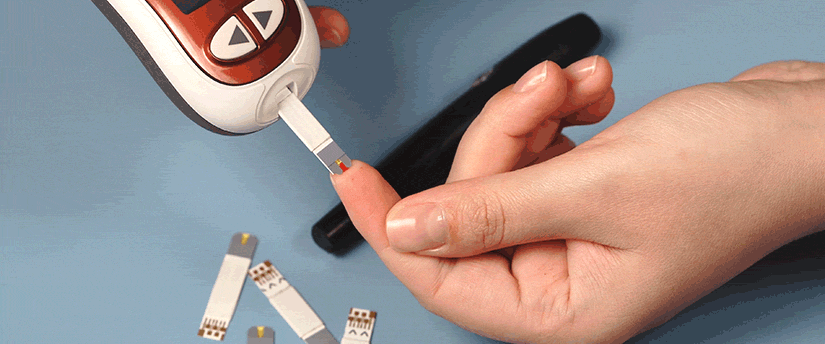 Individual measuring blood sugar with a portable device, focused on the screen.