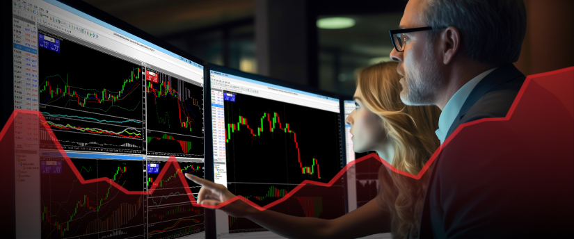 A man and woman analyze a stock market graph displayed on a screen, discussing investment strategies.