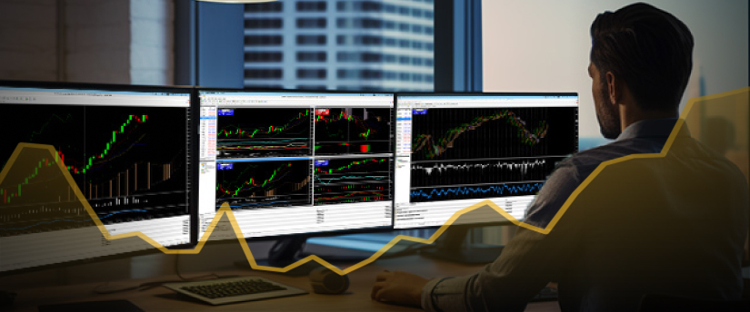 A man at a desk with three monitors displaying various stock market graphs and data analysis.