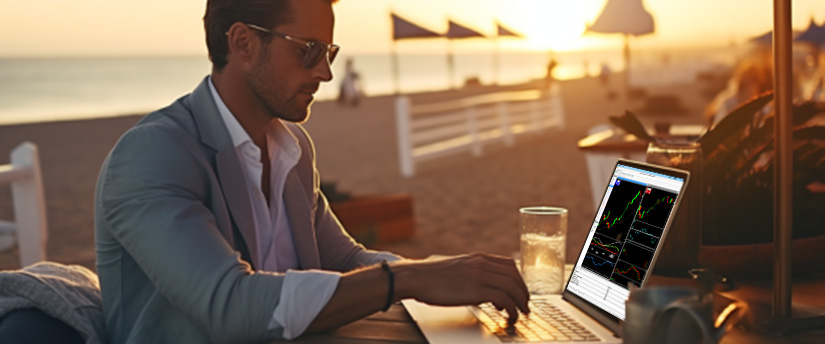 A man at a table with a laptop, engaged in forex CFD trading from anywhere.