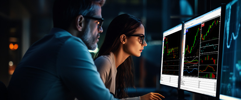 Two people engaged in forex trading, observing market data displayed on a computer screen with concentration.