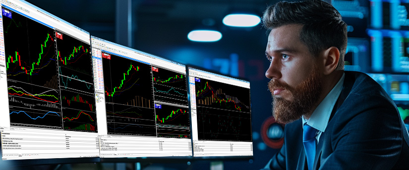 Trader at a desk watching a falling price chart with a moving average line on a monitor